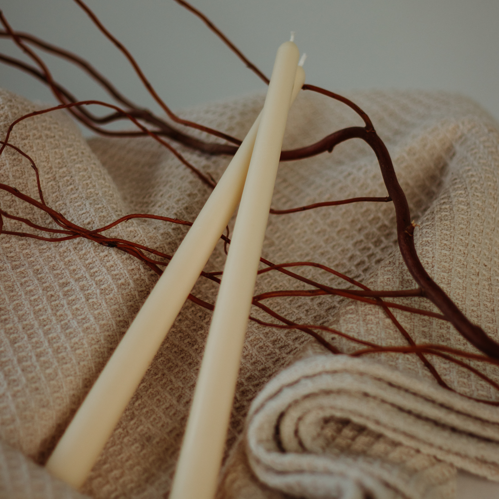 Sojų vaško žvakės subtilaus dizaino ant šilto fono su medžio šakelėmis