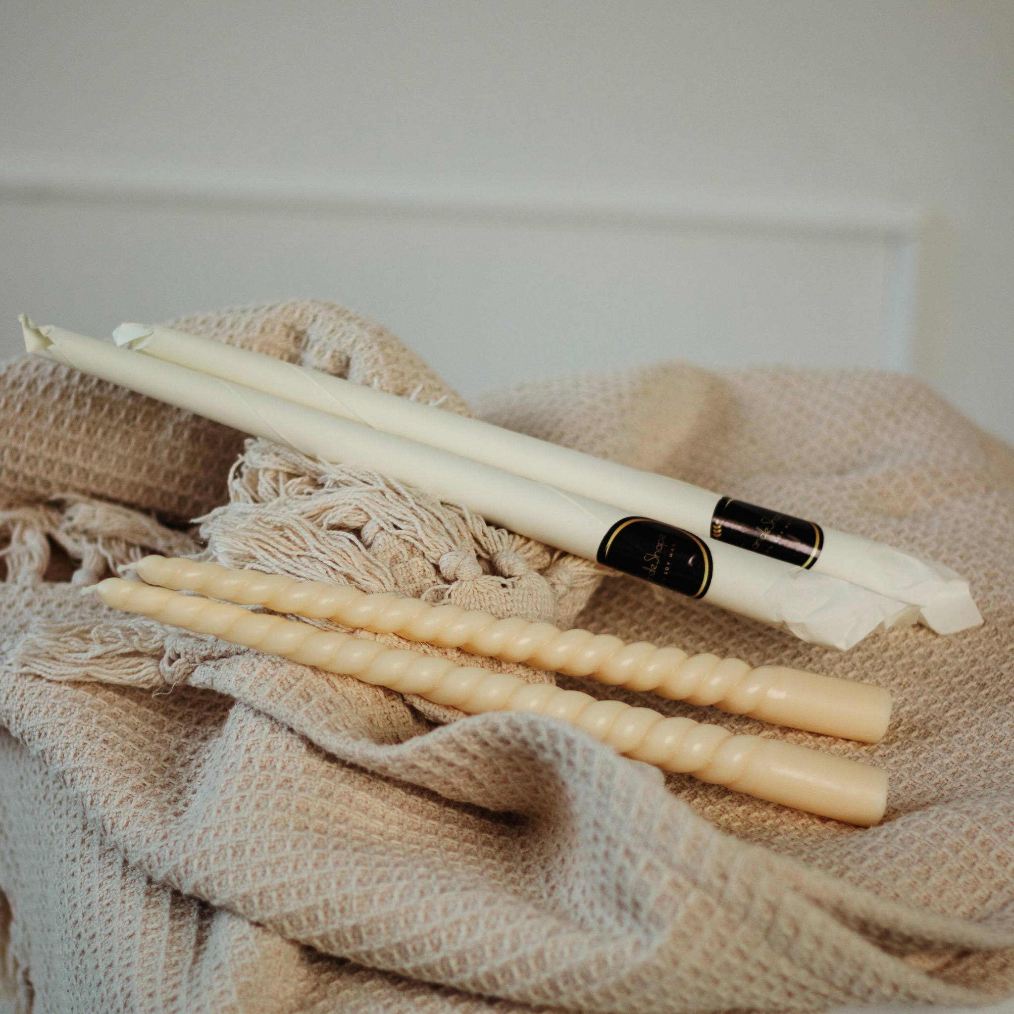 Rapsų vaško stalo žvakės su spiraliniu raštu ir elegantišku dizainu ant audinio fono