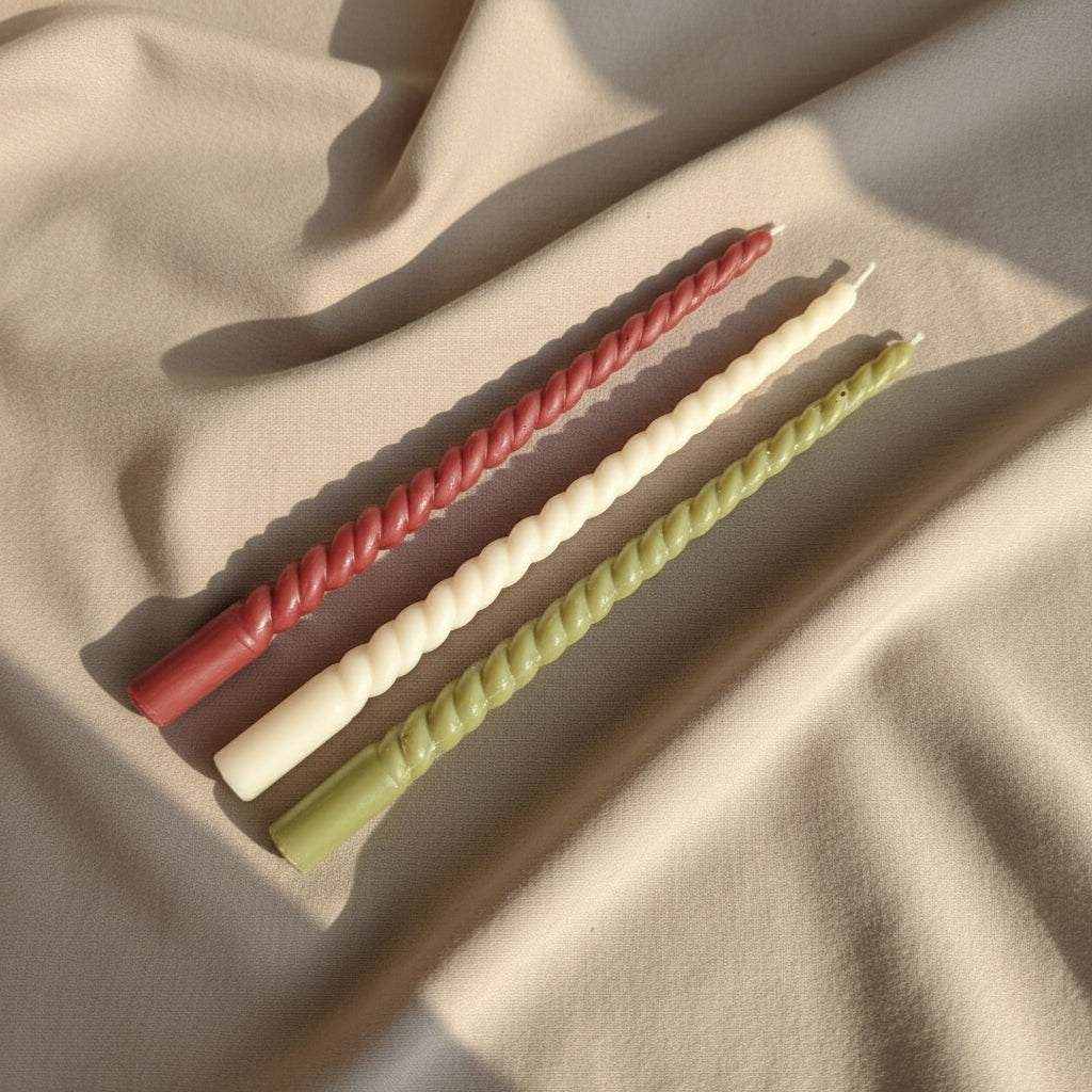 Rapsų vaško spiralės formos stalo žvakės įvairių spalvų ant smėlio spalvos audinio