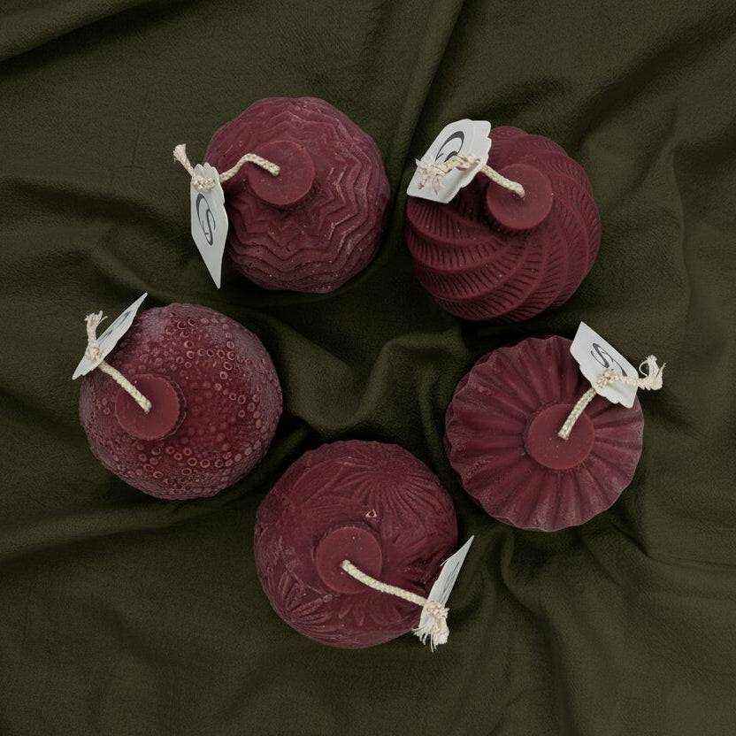 Raudonos rankų darbo rapsų vaško žvakės šventiniame rinkinyje ant tamsaus audinio