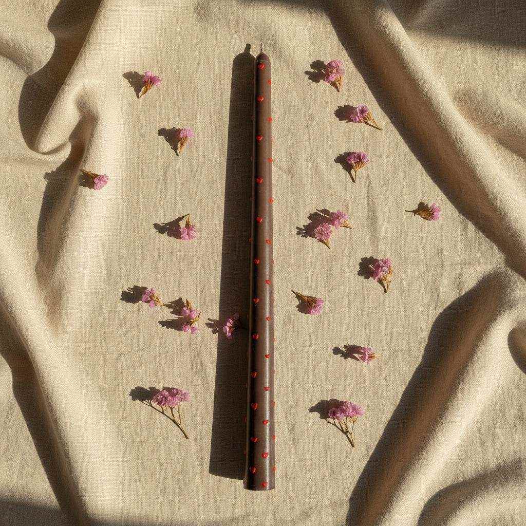 Dekoruota sojų vaško žvakė Slim Glow su raudonais akcentais ant audinio fono