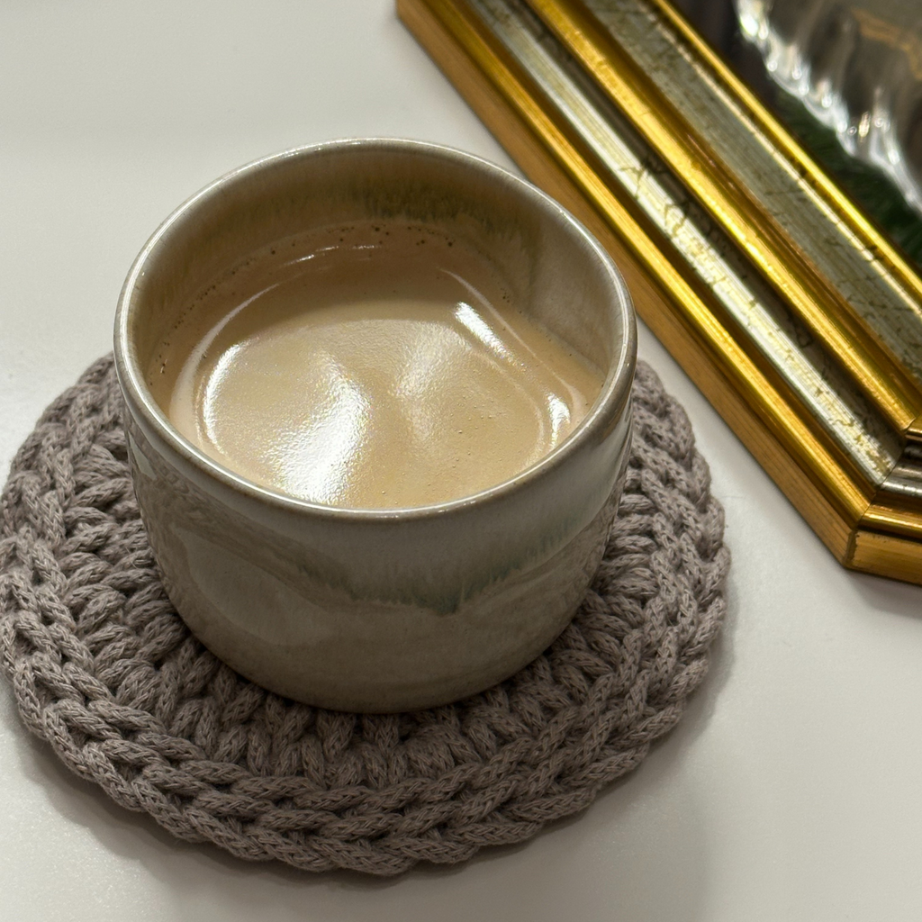 Rankų darbo stalo padėkliukai iš perdirbtos medvilnės „Leo“ su kavos puodeliu ant balto stalo