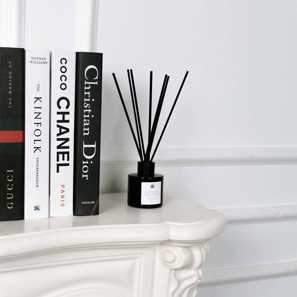 Namų kvapas su rytietišku citrusų ir medienos aromatu ant balto stalo šalia knygų