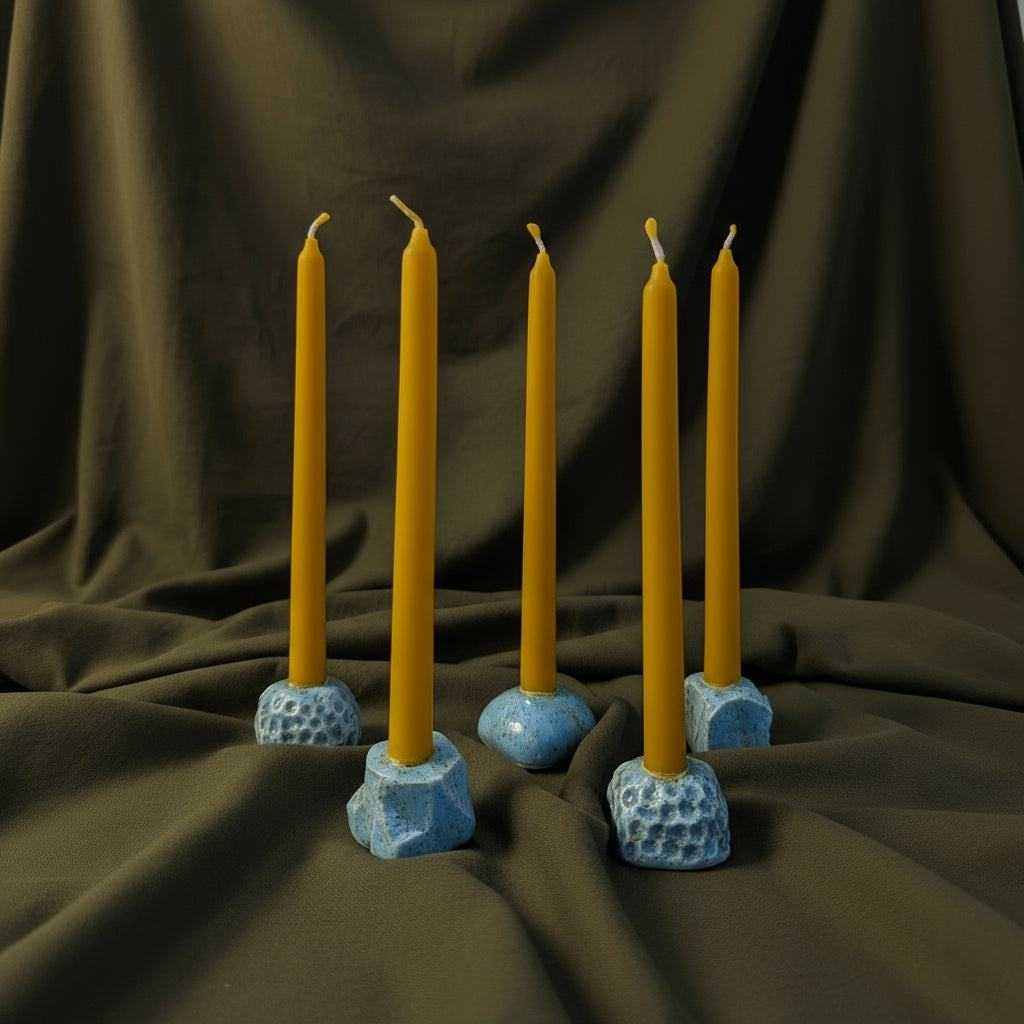 Keraminių mini žvakidžių rinkinys su geltonomis žvakėmis ant tamsios fono tekstūros