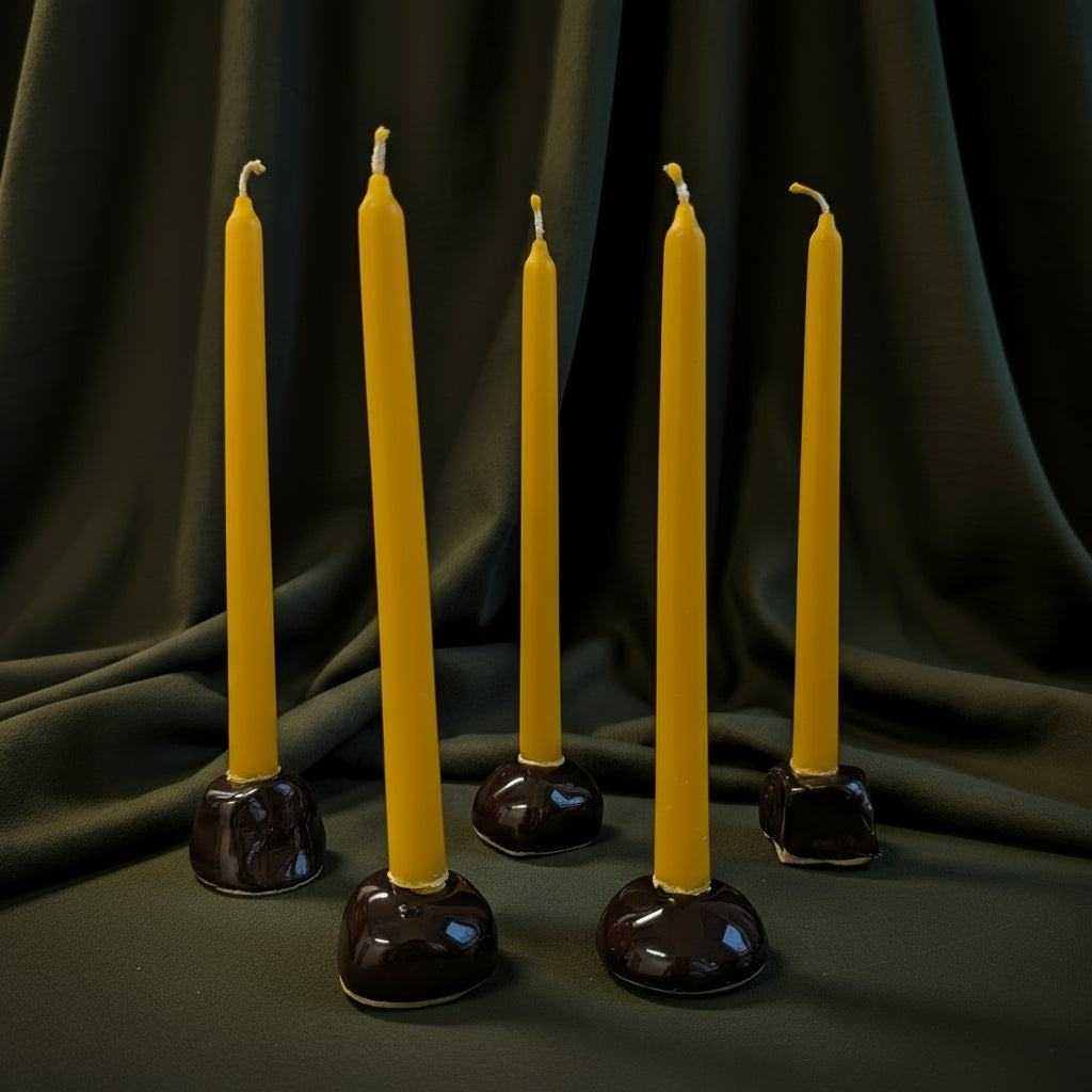 keraminių mini žvakidžių rinkinys su geltonomis žvakėmis ant juodo fono