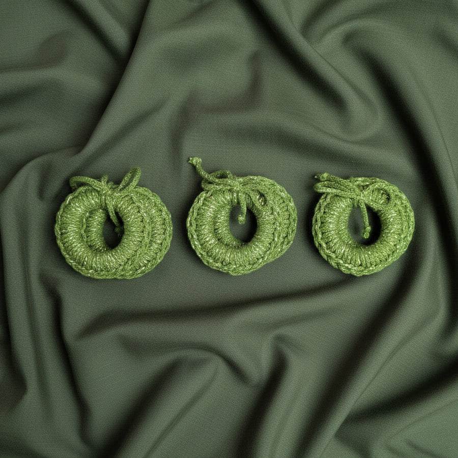 Žali rankų darbo servetėlių žiedai iš perdirbtos medvilnės virvės ant tamsiai žalios medžiagos