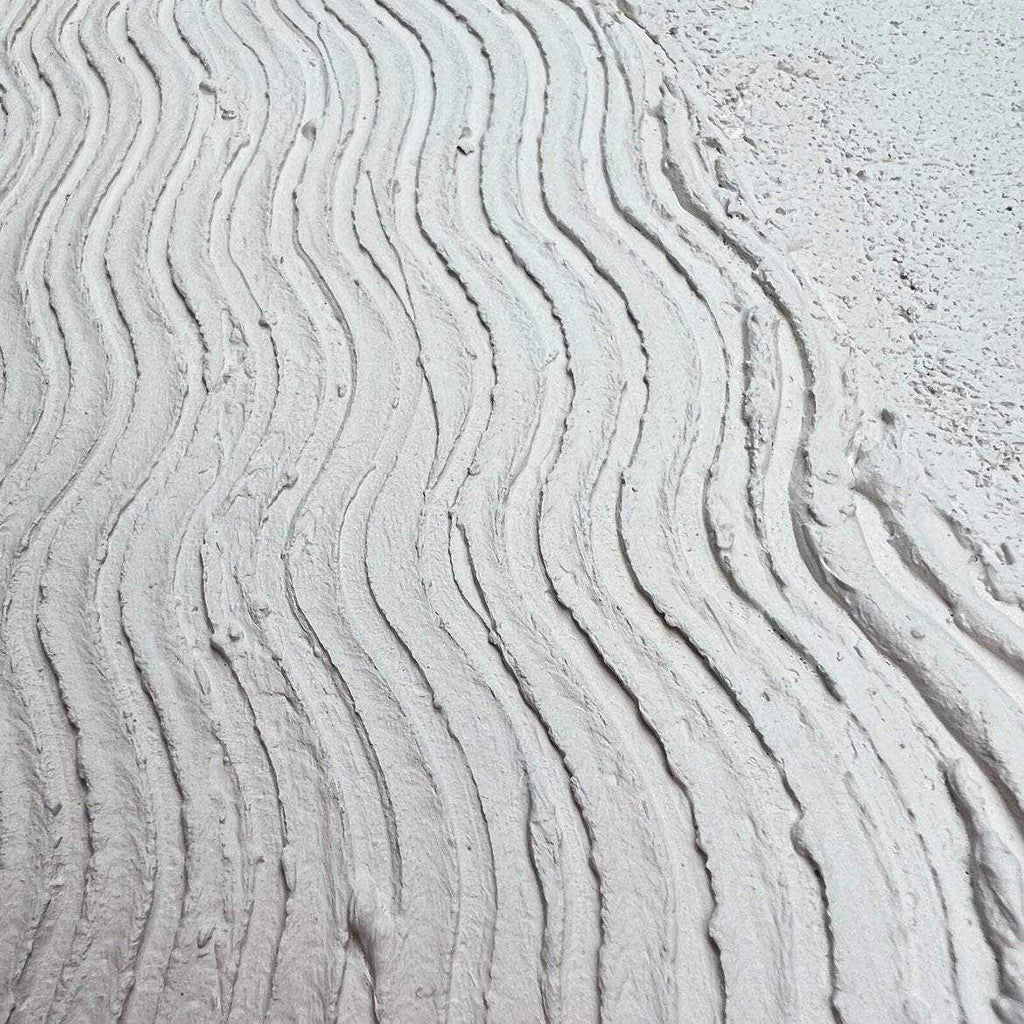 Tekstūrinis paveikslas Prolatio su banguotomis smėlio linijomis ir pirštų prisilietimu